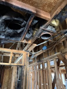 Exposed wiring and ceiling framing in a fire-damaged apartment