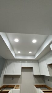 Recessed ceiling lights illuminated above renovated apartment kitchen