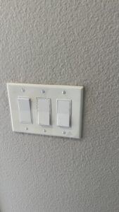 Three wall switches with a white cover plate